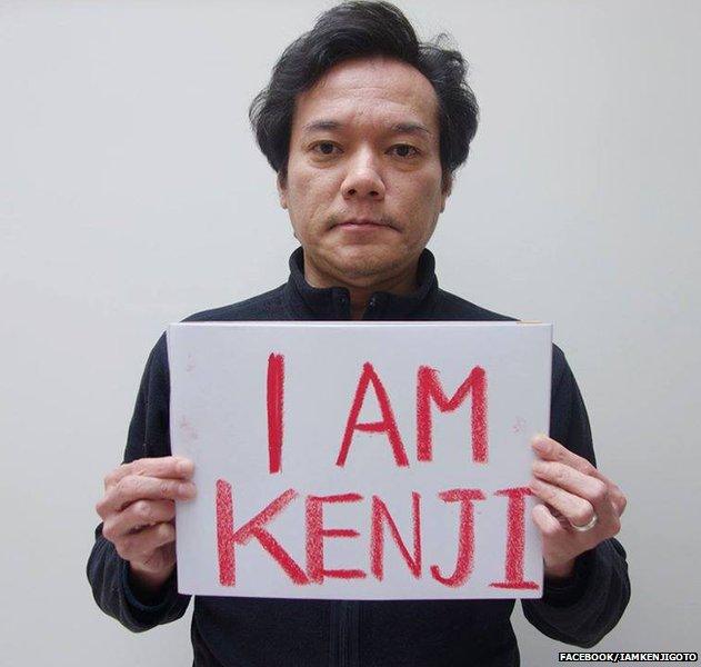 A photo of Taku Nishimae holding a 'I am Kenji' placard