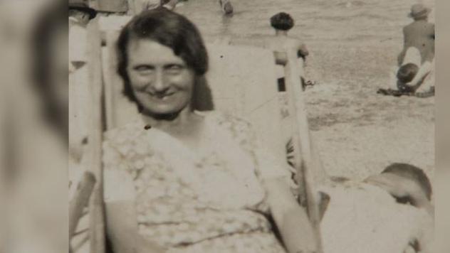 Louisa Dunne sitting in a deck chair facing the camera with other people in the background.
