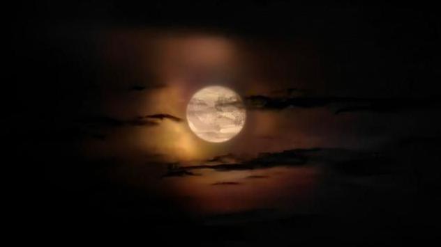 Black clouds with a gap of light in the middle, with a full moon visible.