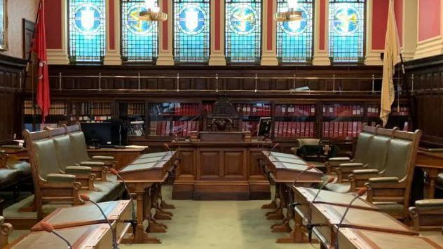 The House of Keys filled with empty chairs and benches below stained glass windows