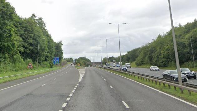 The M606 motorway. The carriageway is clear and on the left-hand side there is a slip road.