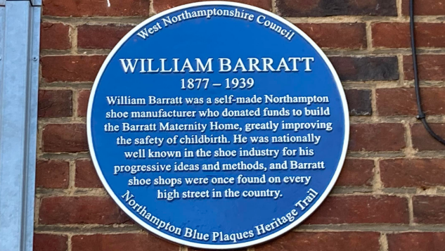 A blue plaque for William Barratt on a brick wall. 