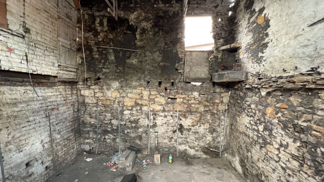 A dark room with old stone walls and a concrete floor