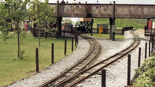 The festival gardens mini railway complete with locomotive in the background and a bridge.