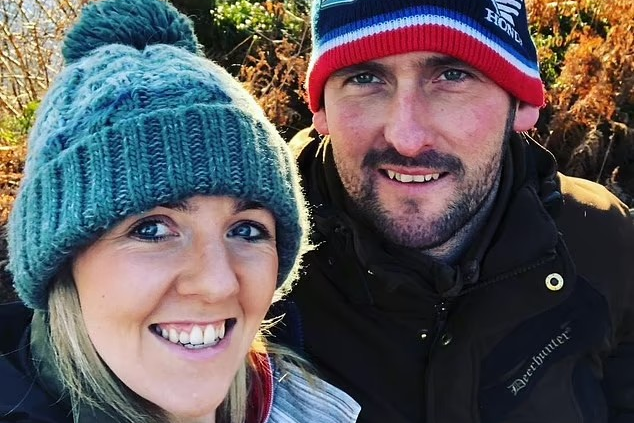 Ricky Rennie and wife Kirsten (left) are wearing woollen hats and jackets with autumn trees behind them. 