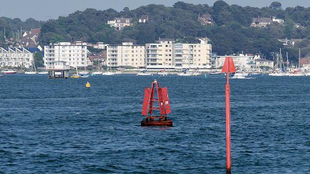 A red metal marker buoy in Poole Harbour