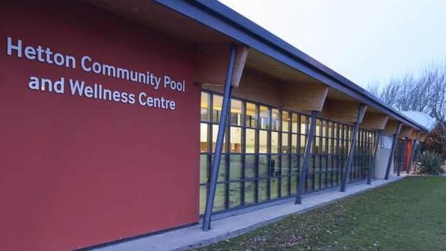 A picture of the front of Hetton Community Pool, it is a long one story building with lots of glass panels through which you can just see the pool 