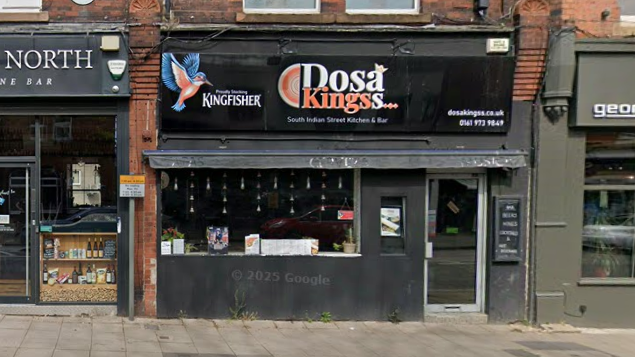 The front of the Dosa Kingss restaurant on the high street, including a black sign above the front window and entrance.