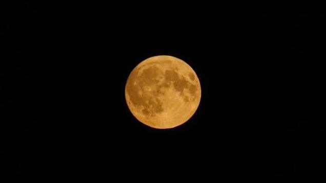 Moon pictured from a distance in yellow/gold hue