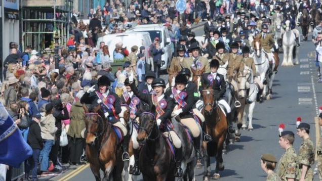 Dozens of horses riding through Berwick with the lead riders wearing sashes