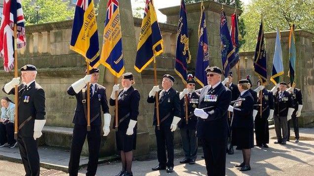 line of RBL members prepare to parade with their flags