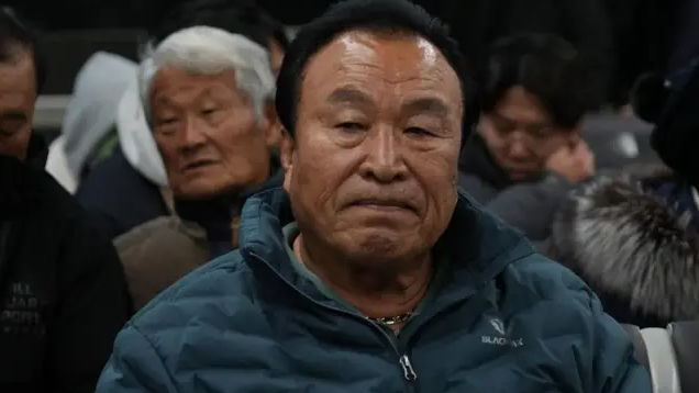 Maeng Gi-su wears a green puffa jacket and a sombre expression.
