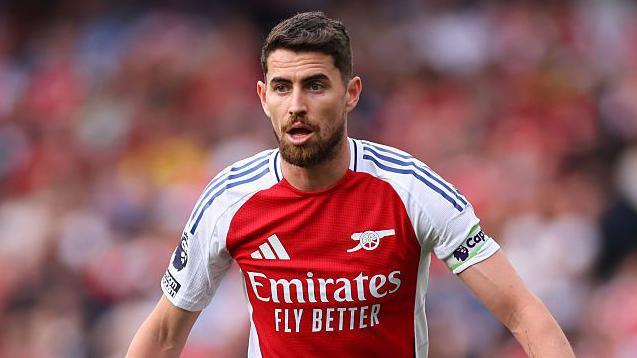 Jorginho wearing a red Arsenal shirt
