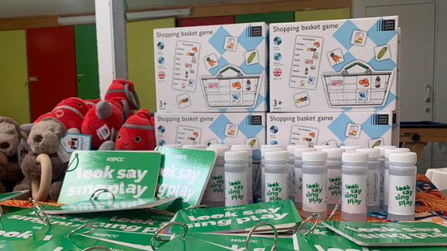 Various resources for Look, Say, Sing and Play, including green booklets, tubes of bubbles, games and cuddly toys on a table