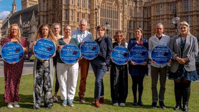 Members of bereaved familes show their relative's black and blue plaques on Westminster's College Green outside parliament