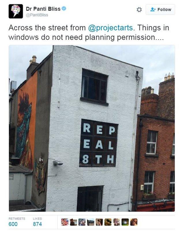 Tweet with photo of building opposite arts centre with window signs saying Repeal the 8th