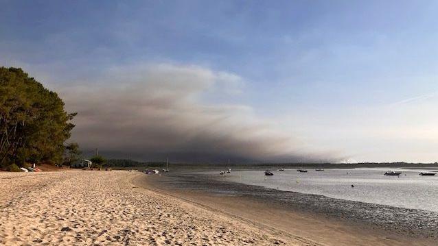 Dark smoke can be seen on the skyline from the beach
