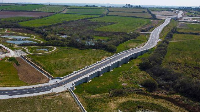 An aerial view of the road which is surrounded by fields with hedges and trees.