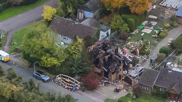 A photo taken by a drone of Cleat Hill after the explosion. Police cars are parked along the street where the destroyed remains of a house can be seen.