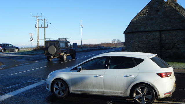 A car at a junction with landrover pulling away