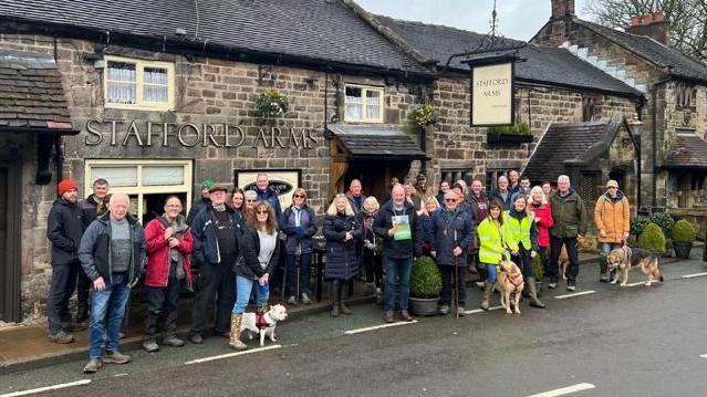 A group of people from Rownall Solar Farm Action Group gather in front of a pub.
