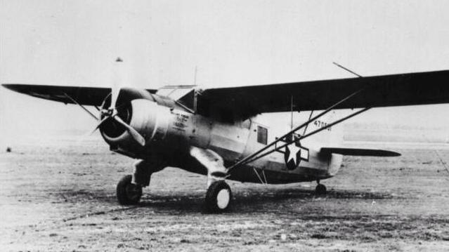 A black and white photo of the C-64 Norseman plane, sitting on a large field with nothing else around. It has one large flat wing spanning both sides over the top, a propeller at the front and two larger wheels below the front of the fuselage, and one small wheel at the back. 