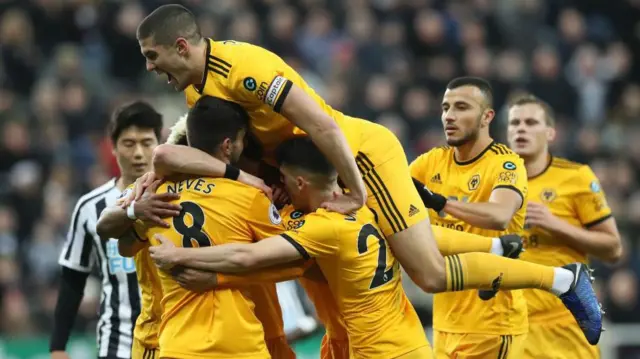 Conor Coady leaps on Ruben Neves and Diogo Jota to celebrate a goal for Wolves