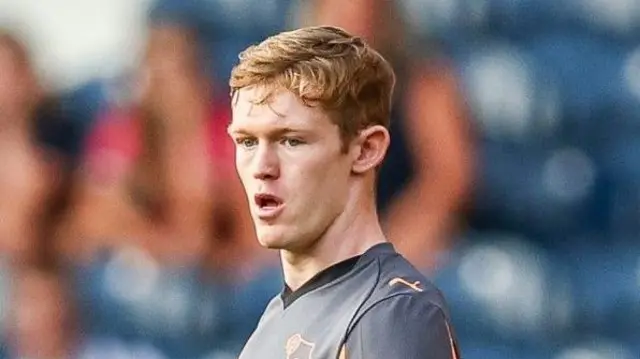 Jake Rooney wearing a grey and orange Derby County away jersey during a match.