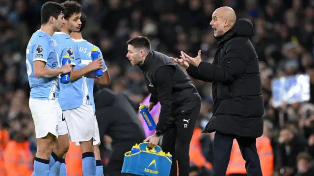 Pep Guardiola, manager of Manchester City, speaks with Abdukodir Khusanov