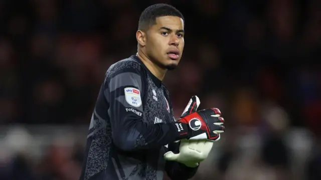 Seny Dieng holding the ball in a dark Middlesbrough goalkeeping jersey during a game
