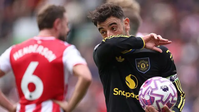 Bruno Fernandes holds the ball in his hands as Man Utd take on Brentford. He wipes his nose with his sleeve.