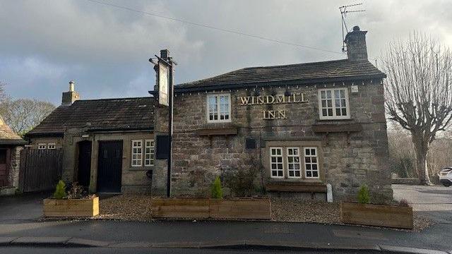 The exterior of a rural pub, made of stone. 