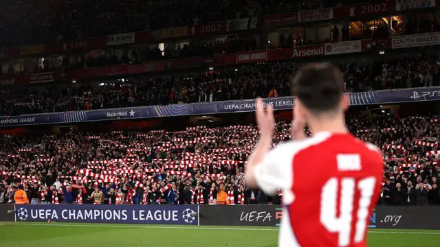 Arsenal fans hold their scarves aloft as Declan Rice of Arsenal applauds them