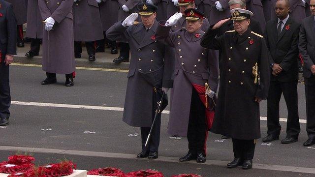 Three veterans saluting the Cenotaph, having laid a wreath