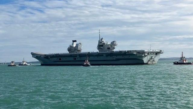The large carrier at sea next to tug boats