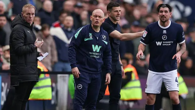 Millwall boss Alex Neil and defender Tristan Crama look on during Millwall's defeat to Portsmouth, with Pompey boss John Mousinho passing on instructions to his players in the background