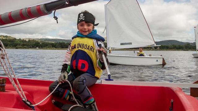 Jac yn ifanc mewn cwch hwylio