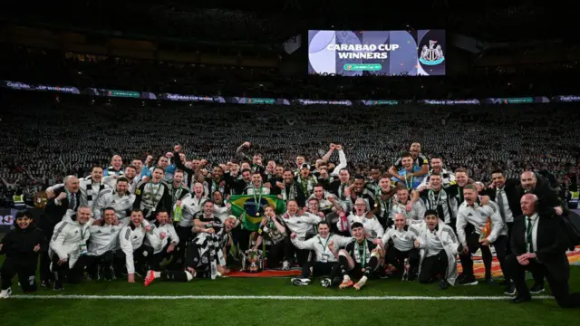 Newcastle players and staff with the trophy in front of the fans