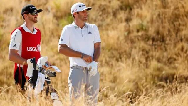 Dustin Johnson waits with his caddie