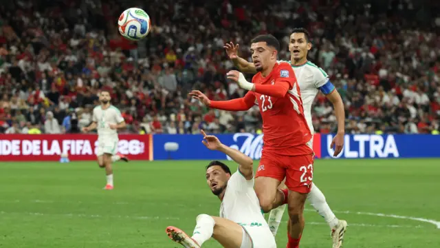 Zeki Amdouni, wearing his red Switzerland kit, competing for the ball against Algerian players during their World Cup match on Friday