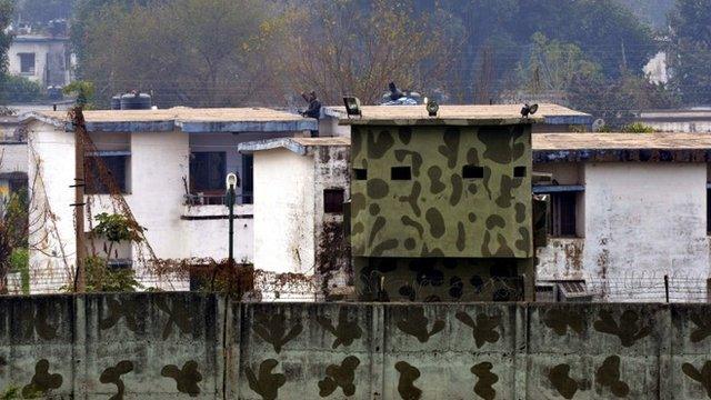 Indian air force personnel stand on the roof of a building at the base in Pathankot