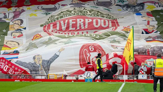 A giant Liverpool flag is unfurled on The Kop