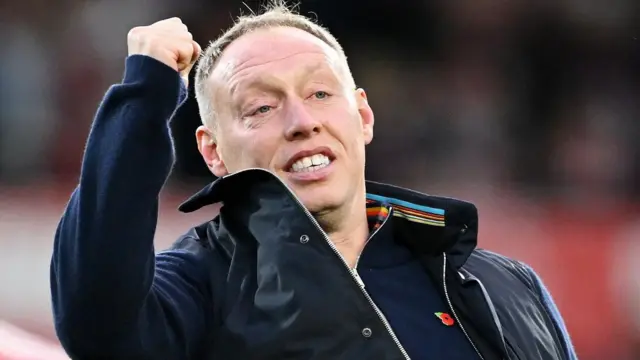 Steve Cooper raises his right arm and clenches his fist in celebration while Nottingham Forest manager