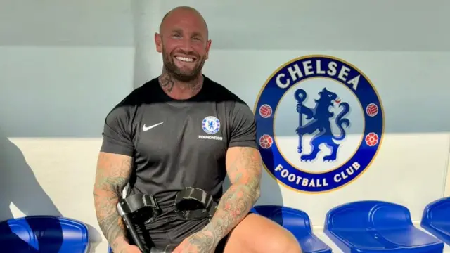 Mark Smith sitting in a dugout holding crutches