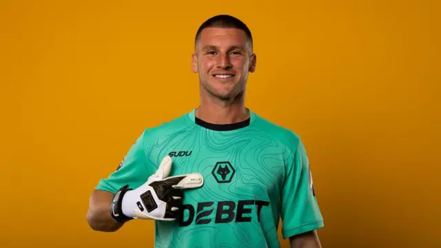 Sam Johnstone pointing at the Wolves badge