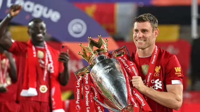 James Milner of Liverpool poses for a photo with The Premier League trophy