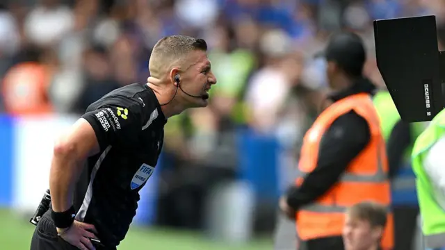 Match referee Robert Jones checking the VAR screen.