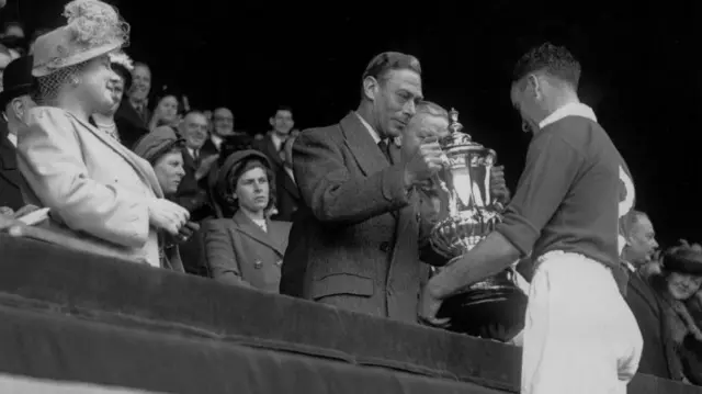 Manchester United captain Johnny Carey is presented with the FA Cup following the victory over Blackpool by King George VI at Wembley in 1948