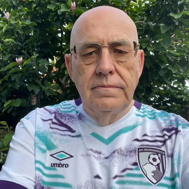 A man takes a selfie in a Bournemouth away shirt