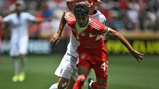 Bayern Munich's Moroccan defender #49 Adam Aznou (front) fights for the ball with Auckland City's New Zealander forward #07 Myer Bevan during the Club World Cup 2025 Group C football match between Germany's Bayern Munich and New Zealand's Auckland City at the TQL stadium